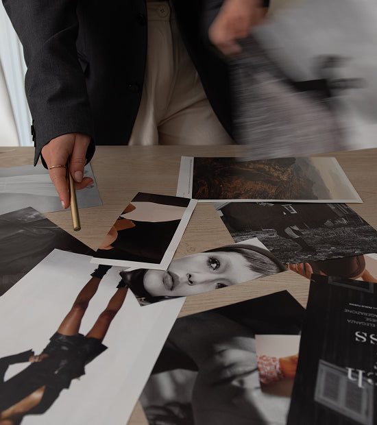Person sorting through fashion magazine clippings on a table.