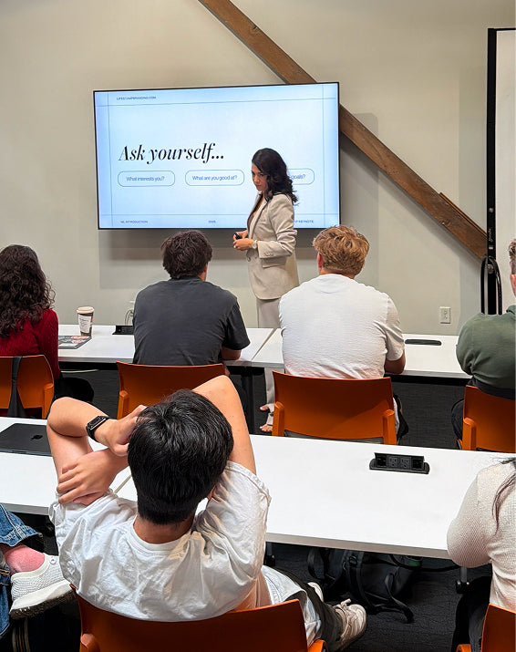 Person giving a presentation to an audience in a classroom setting.