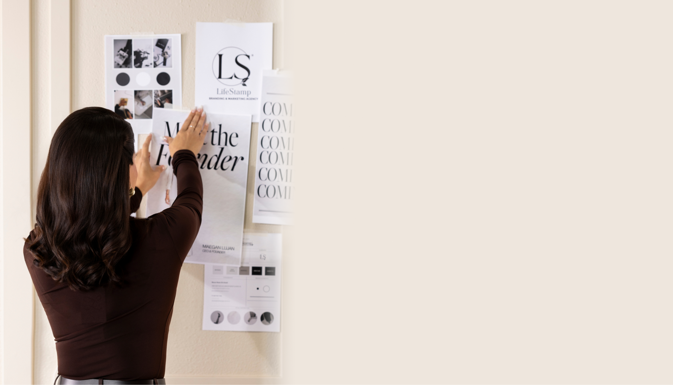Person arranging design elements on a wall with posters and notes.