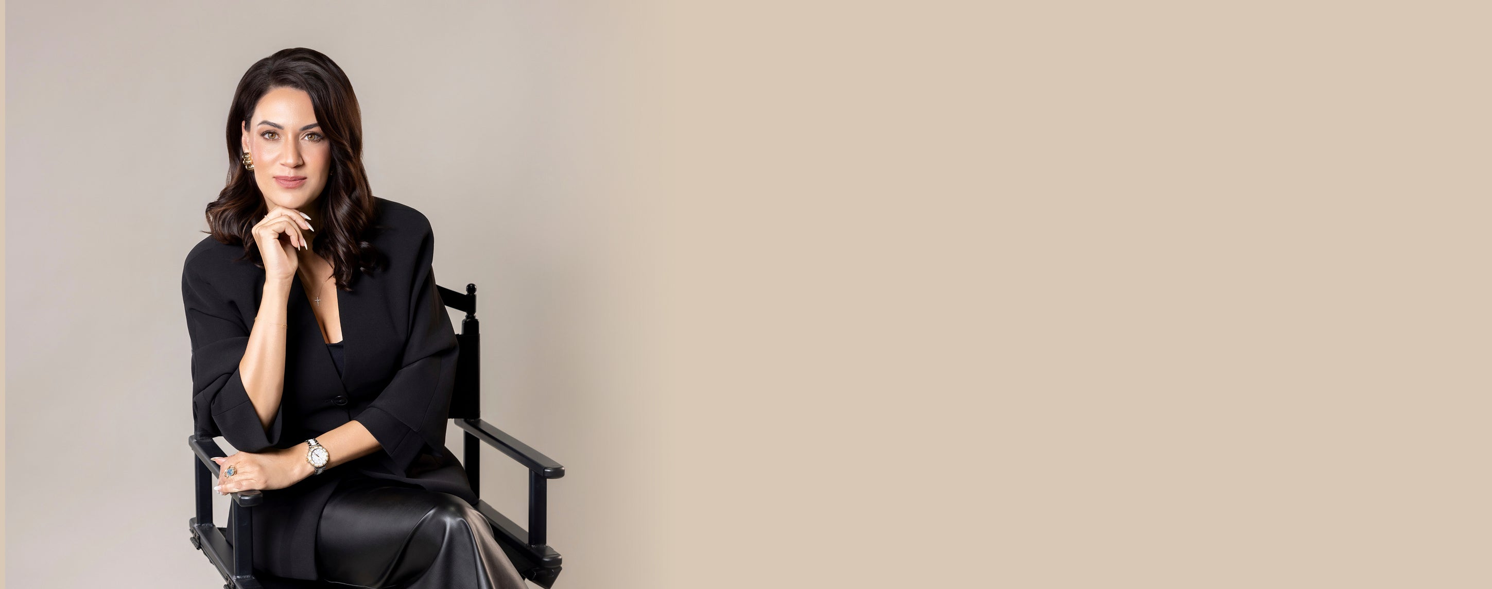 Woman sitting on a director's chair against a plain background